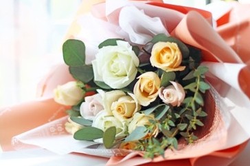 Wrapped bouquet of cream and peach roses
